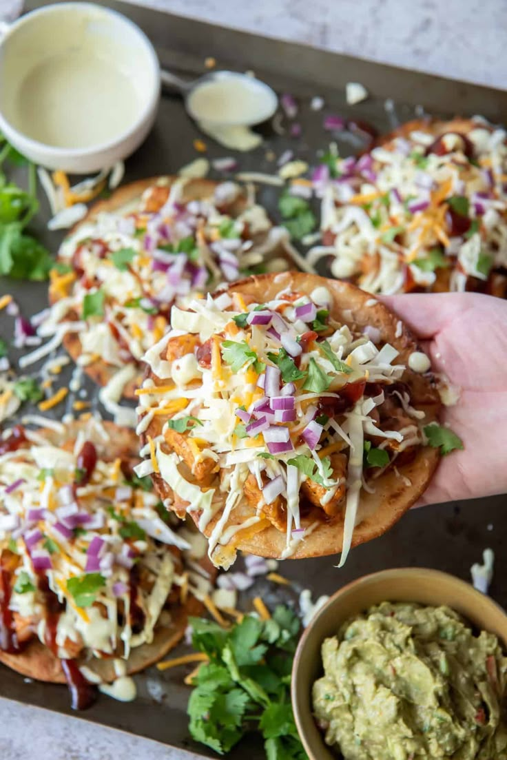 someone is holding up a taco salad on a tray with guacamole and tortilla chips