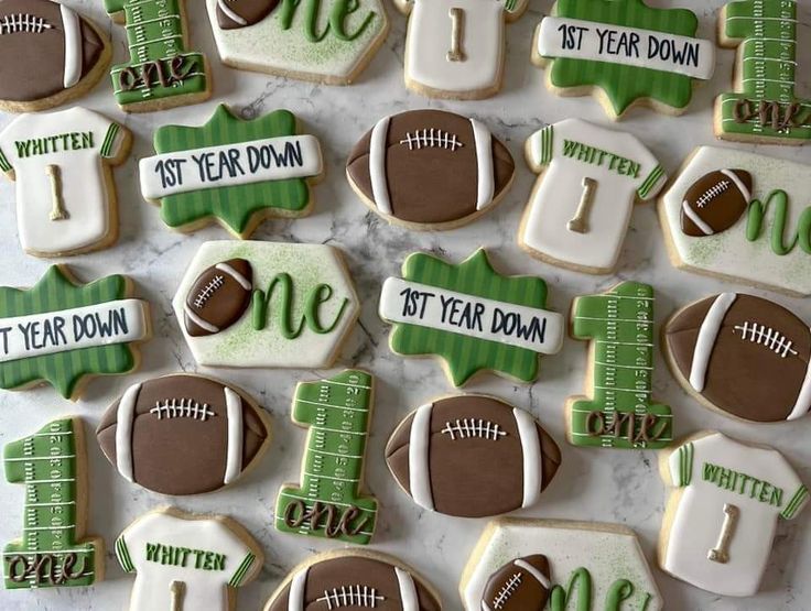 decorated cookies are arranged on a table for a football themed birthday party, with green and white icing