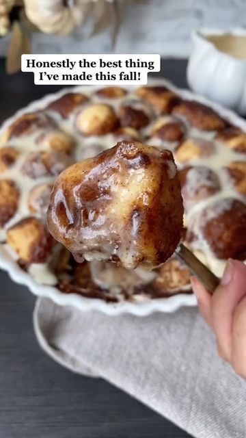 a person holding a pastry in front of a plate with other desserts on it