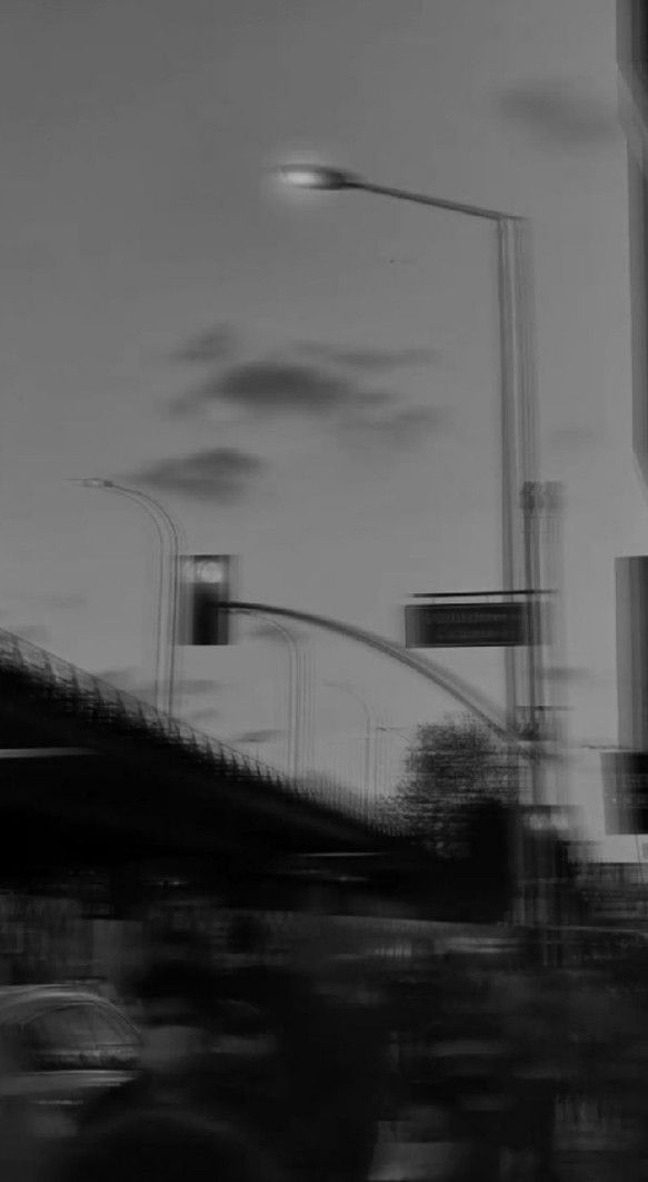 a blurry photo of traffic lights and street signs in black and white with an overcast sky