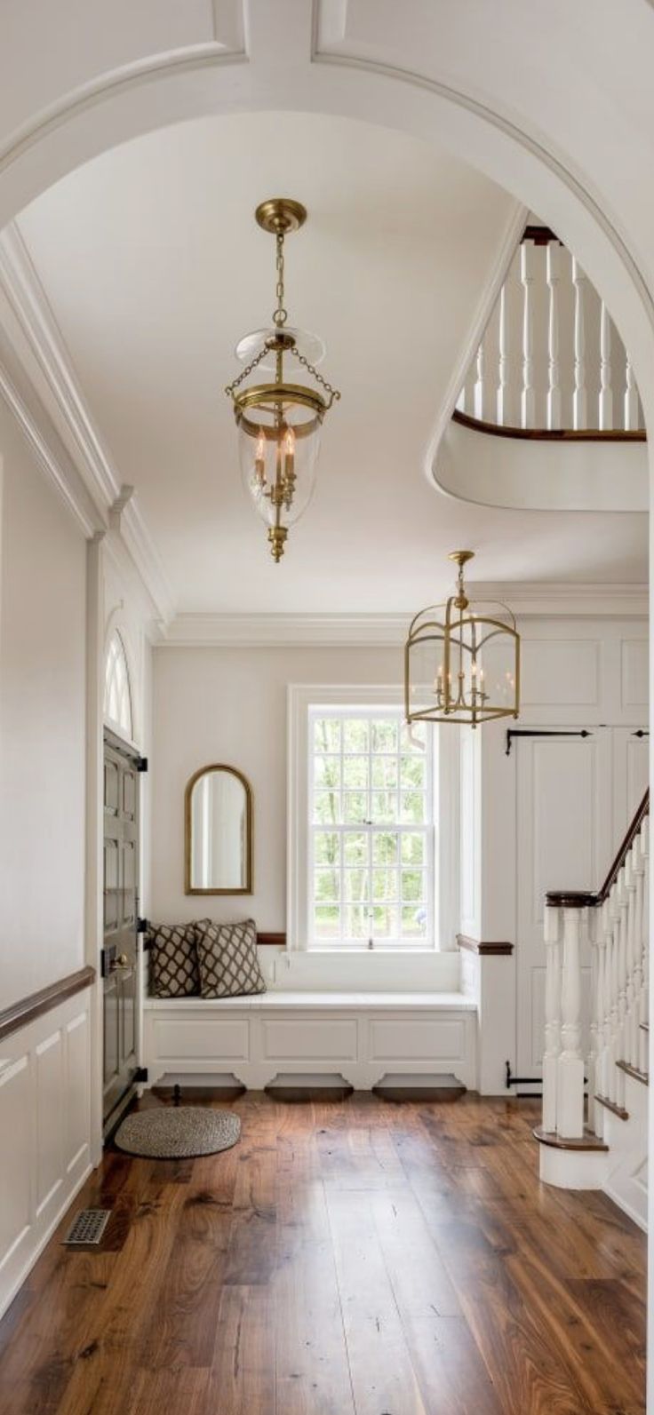 an archway leading to a living room with hardwood floors and white walls, along with a chandelier hanging from the ceiling