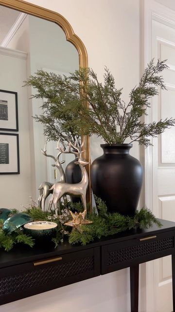 a black vase sitting on top of a table next to a mirror and other decorations