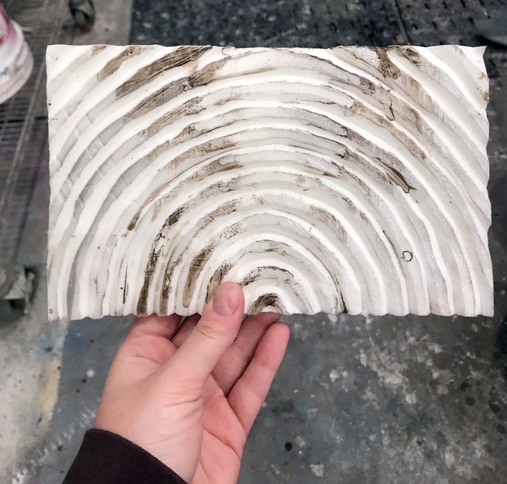 a hand is holding up a piece of white paper that looks like an interlocked spiral