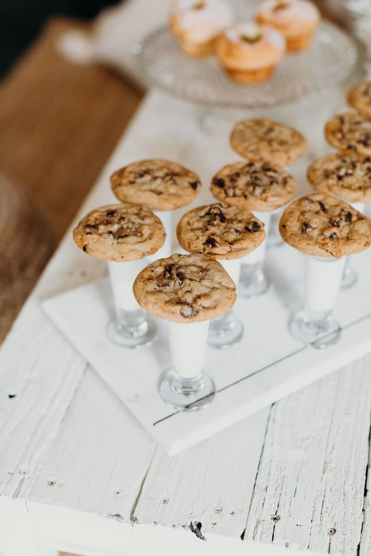 cookies and muffins are arranged on a white tray next to some wine glasses