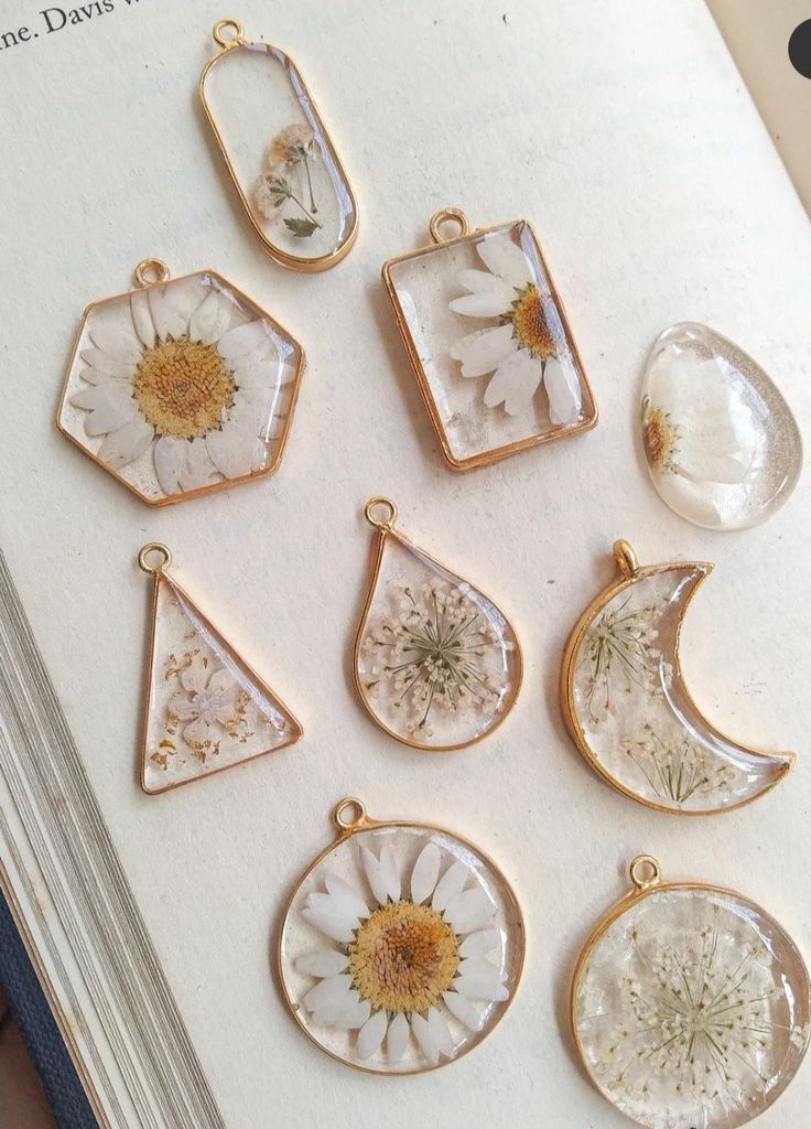 the book is open to show nine different pendants with flowers and leaves on them