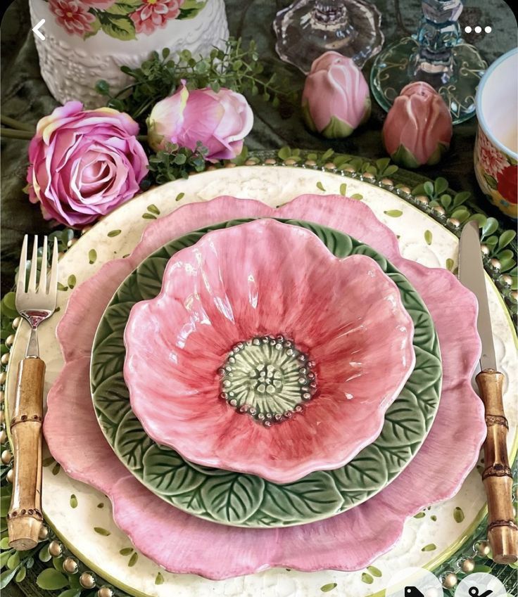 a pink flower is sitting on top of a green and white plate with silverware