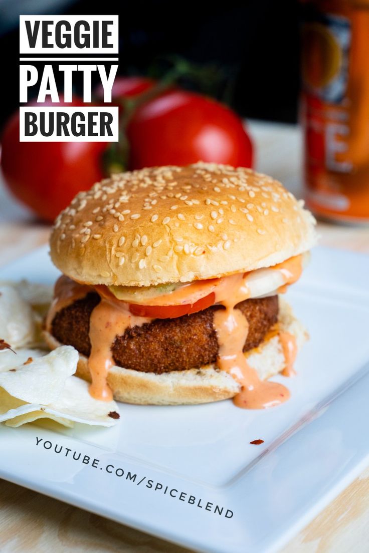 a chicken sandwich on a bun with ketchup and lettuce is sitting on a plate next to tomatoes