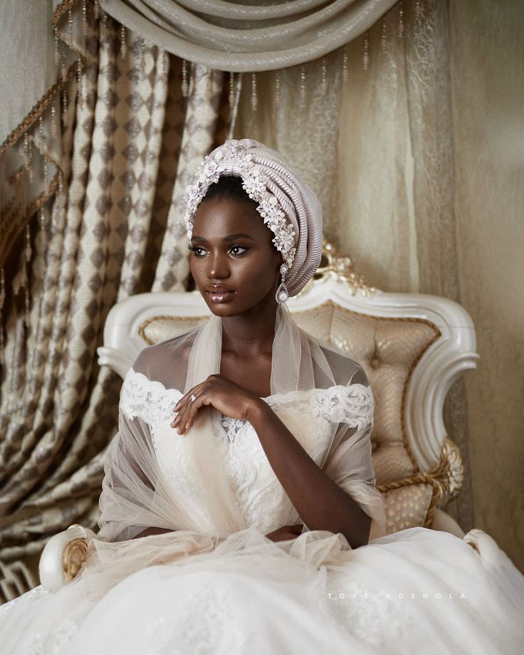 a woman in a white dress sitting on a bed wearing a turban and veil