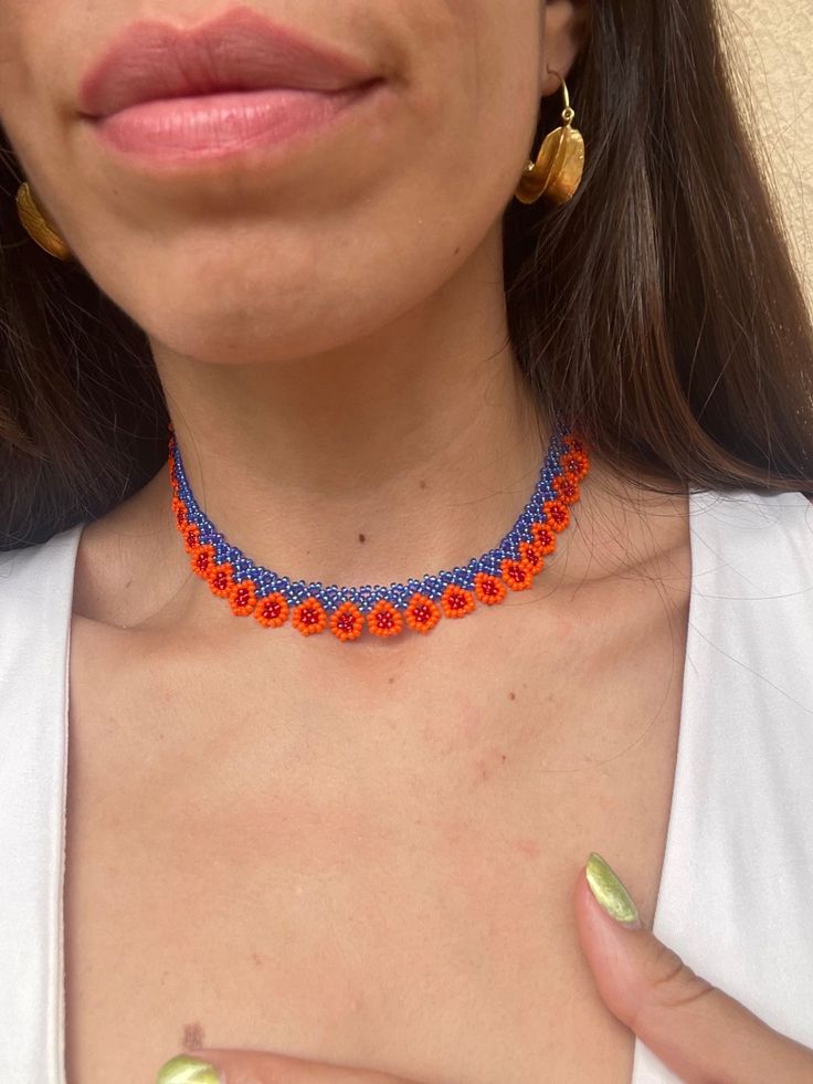 a close up of a woman wearing an orange and blue beaded choker necklace