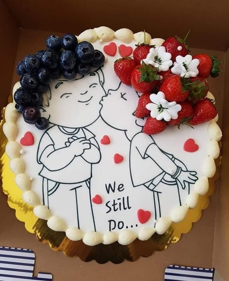 a cake decorated with strawberries and blueberries is in a box that says we still do