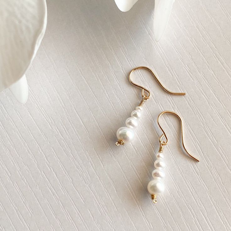 "This beautifully simple pair of dangle earrings are lovingly handmade with eight tiny Freshwater Pearls and a choice of a 14k Solid Gold, 14k Gold Filled, 14k Rose Gold Filled or Sterling Silver finish. M A T E R I A L S: * Freshwater Pearl  * 14k solid Gold, 14k Gold Filled, 14k Rose Gold Filled or Sterling Silver S I Z E: *  Gemstone - Approximately 3-6mm All of our jewellery is carefully handmade using good quality materials and handpicked gemstones, with the aim to produce quality pieces that you can love & wear for years to come.  P E A R L: * June Birthstone * Talisman for Gemini, Cancer * Third Eye Chakra Pearl signifies faith, charity and innocence. It enhances personal integrity and helps to provide a focus to ones attention. Pearl symbolises purity and is known as a \"stone of s Tiny Pendant Necklace, Pearl Jewelery, Pink Gemstone Necklace, Drop Earrings Simple, Tiny Pendant, Dangle Earrings Silver, Gemstone Drop Earrings, White Jewelry Box, Pearl Dangle Earrings