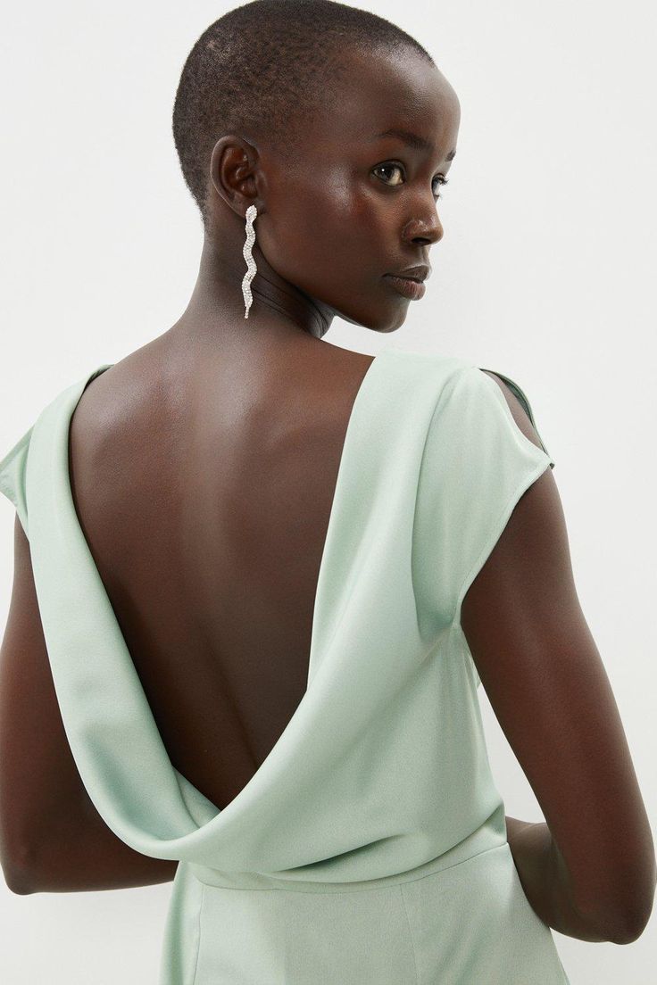 the back of a woman's dress, with her hands on her hips and looking off to the side