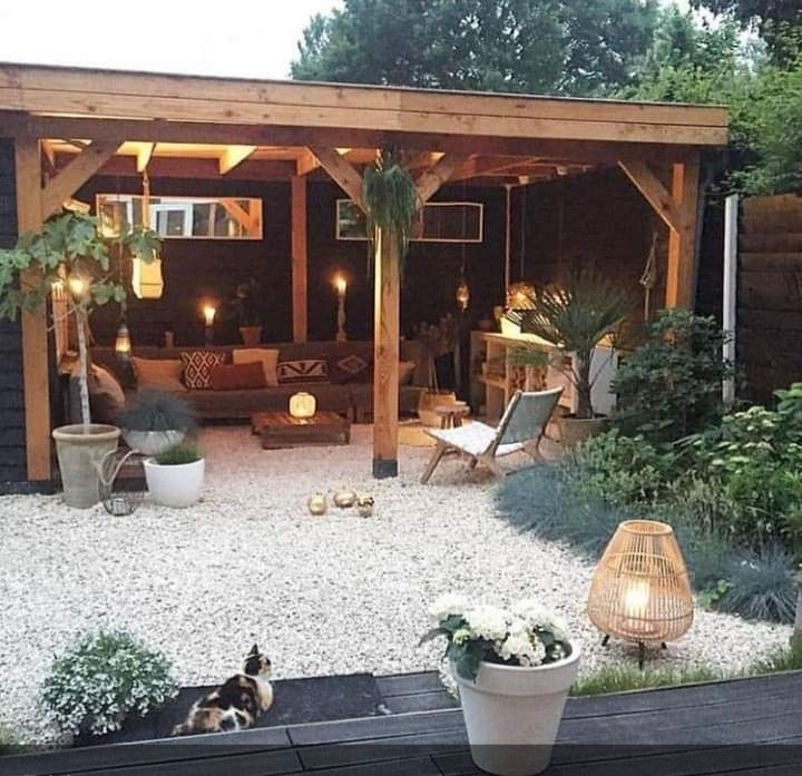 an outdoor living area is lit up with lights and potted plants in the foreground