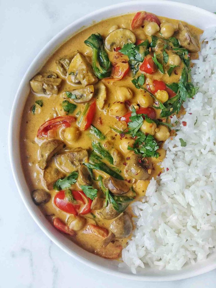 a white plate topped with rice and vegetables next to a bowl of chicken curry on top of rice