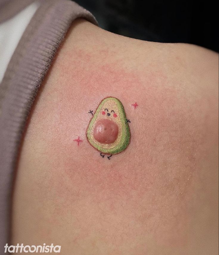 an avocado tattoo on the back of a woman's shoulder with stars around it