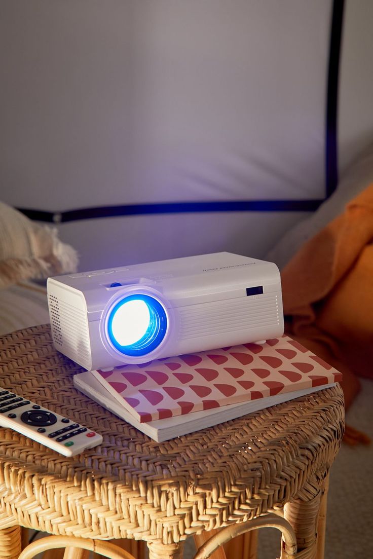 a white projector sitting on top of a table next to a remote control and lamp