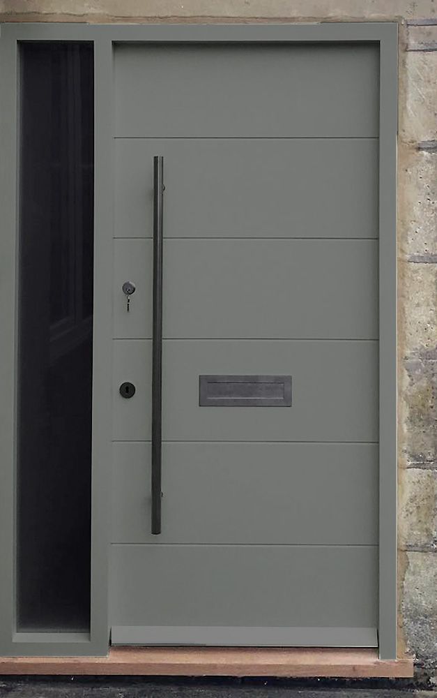 a gray door with a black handle on the side and brick wall in the background