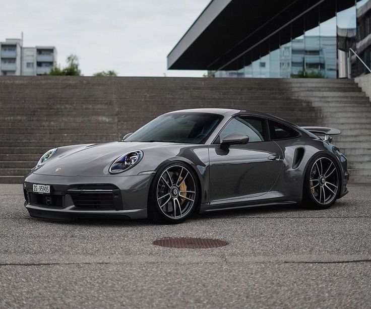 a grey sports car parked in front of some stairs and steps on a cloudy day