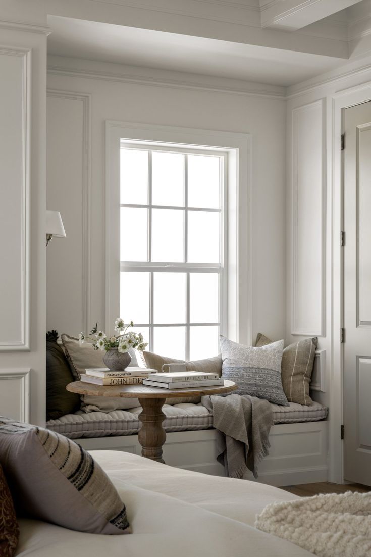 a bedroom with white walls and pillows on the bed in front of a large window