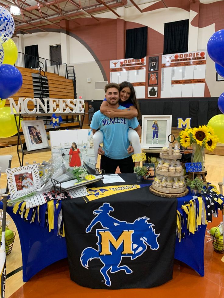 a man and woman standing in front of a table covered with balloons, pictures and decorations