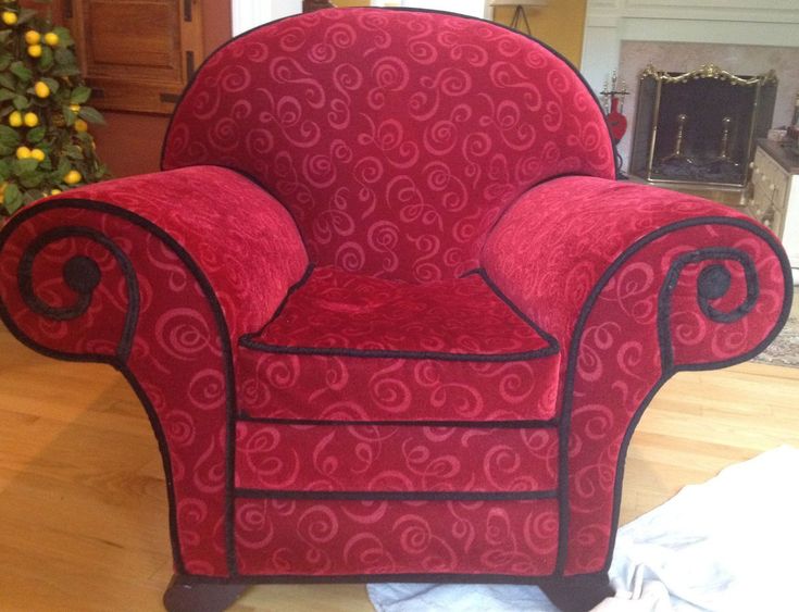 a red chair sitting on top of a hard wood floor next to a christmas tree