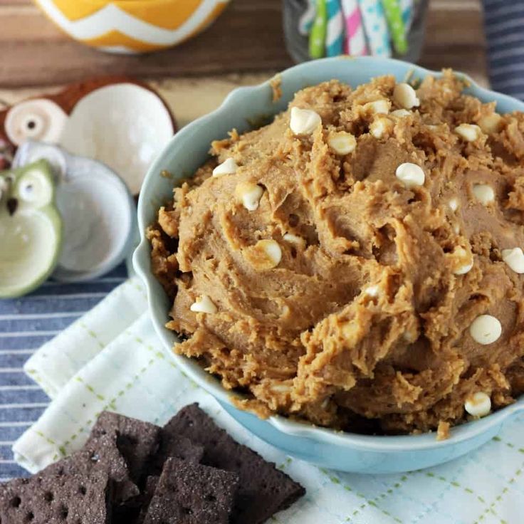 a blue bowl filled with food next to crackers and candy canes on a table