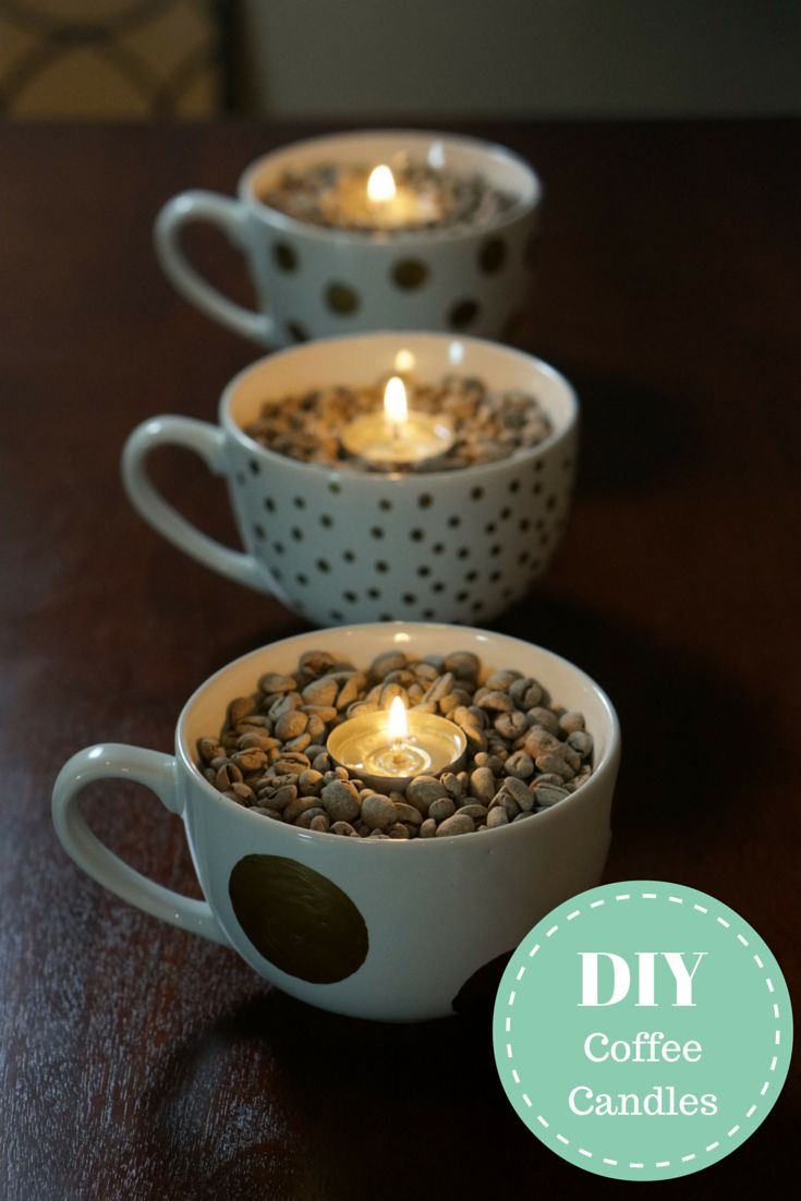 three coffee mugs with candles in them sitting on a table