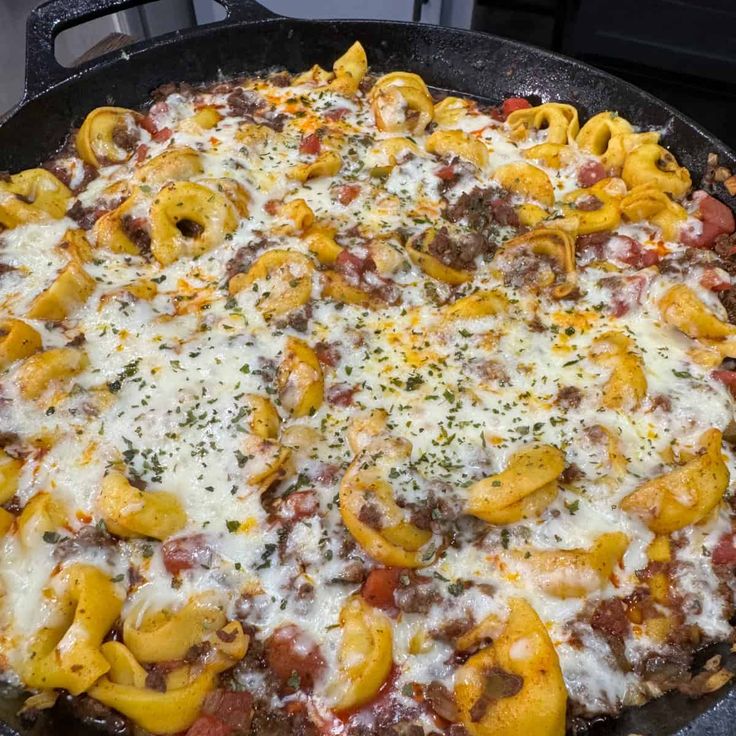 a pizza covered in cheese and meat sitting on top of a stove