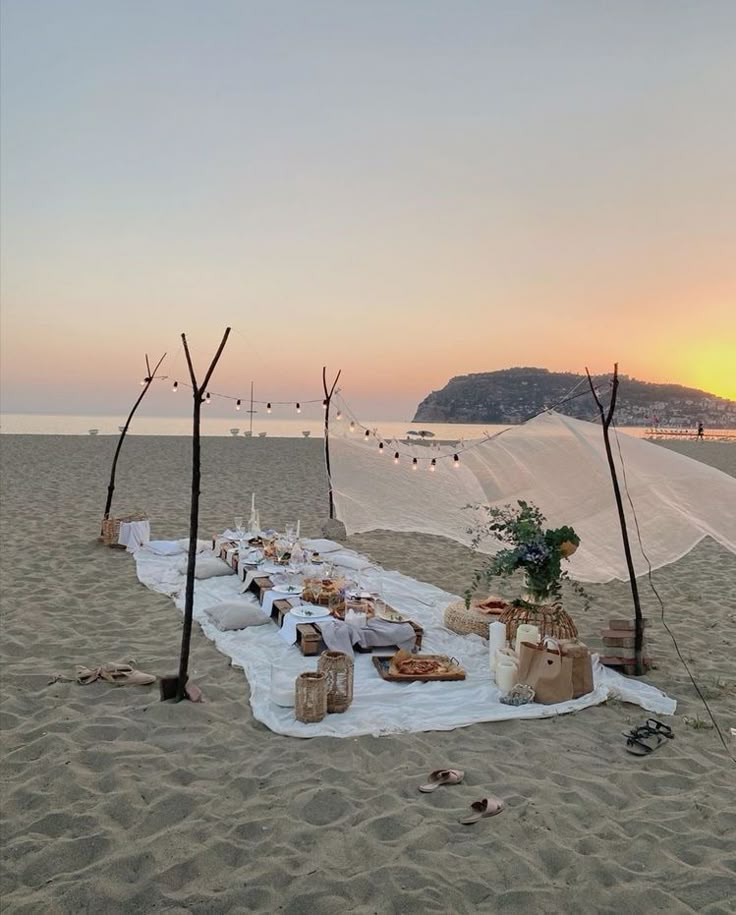 a long table set up on the beach at sunset