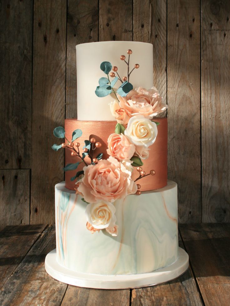 a multi - tiered cake with flowers on it is sitting on a wooden table