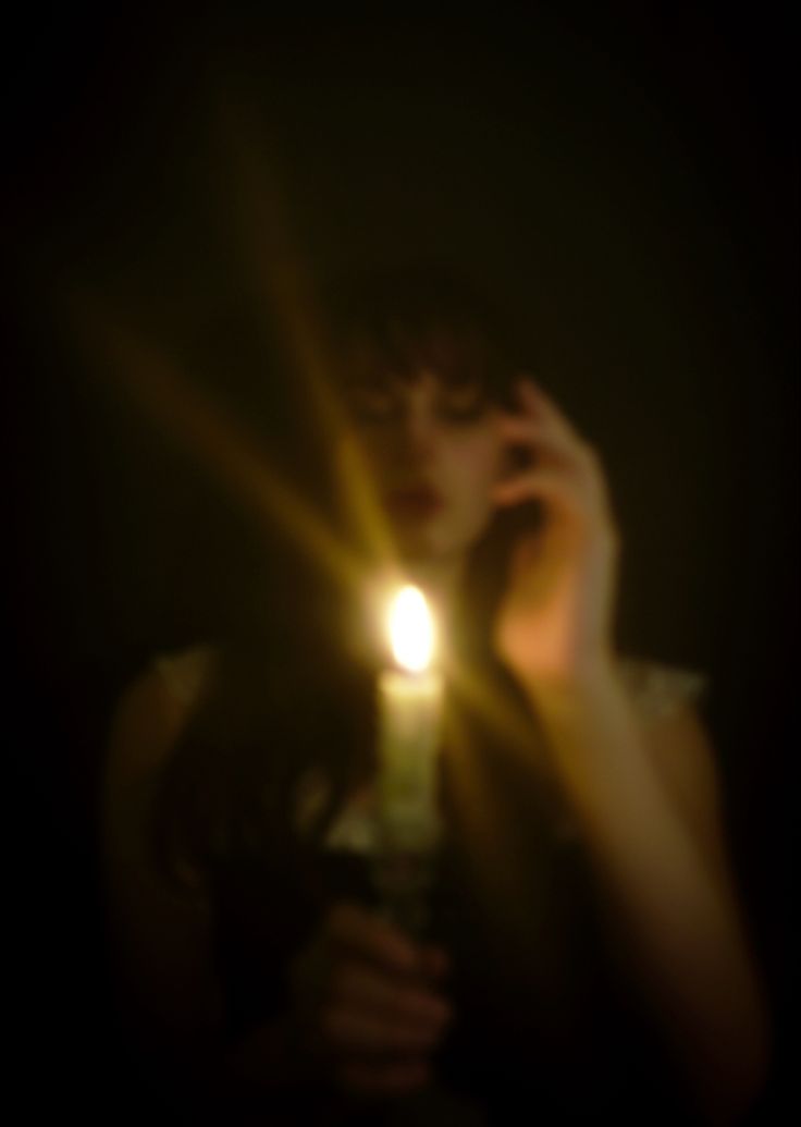 a woman holding a cell phone up to her face with the light shining on her