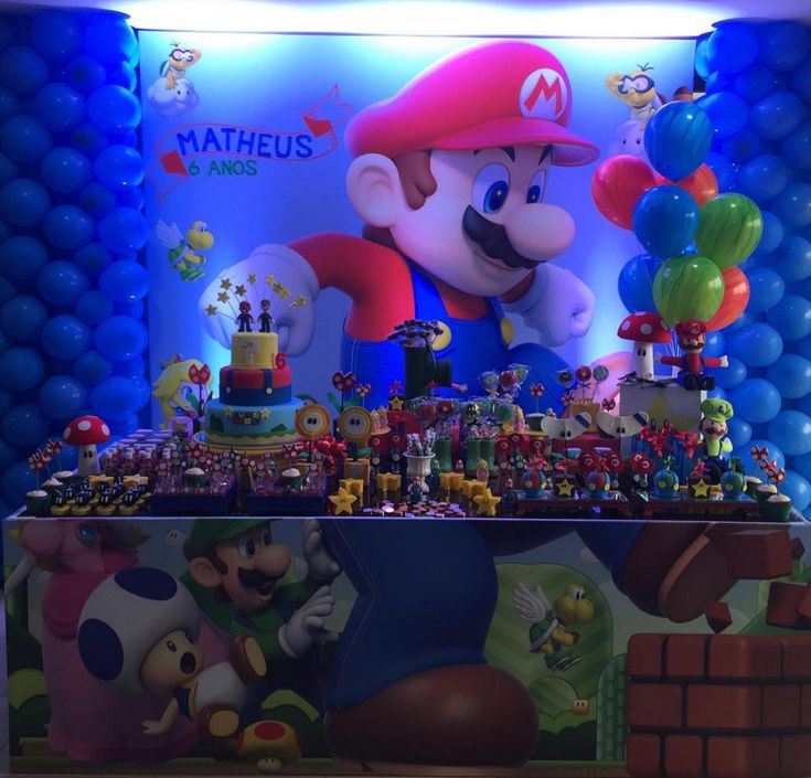 a mario birthday party setup with balloons and decorations on the wall, including an over - sized cake