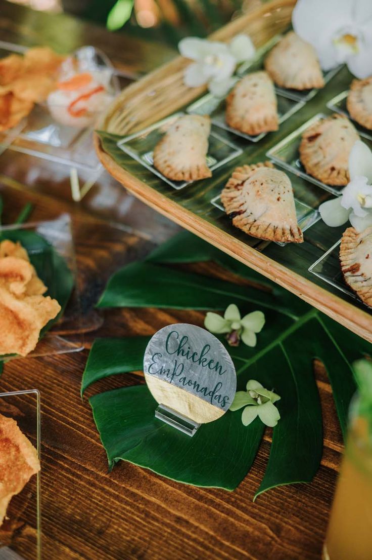 there are many small pastries on the trays that have flowers and leaves around them