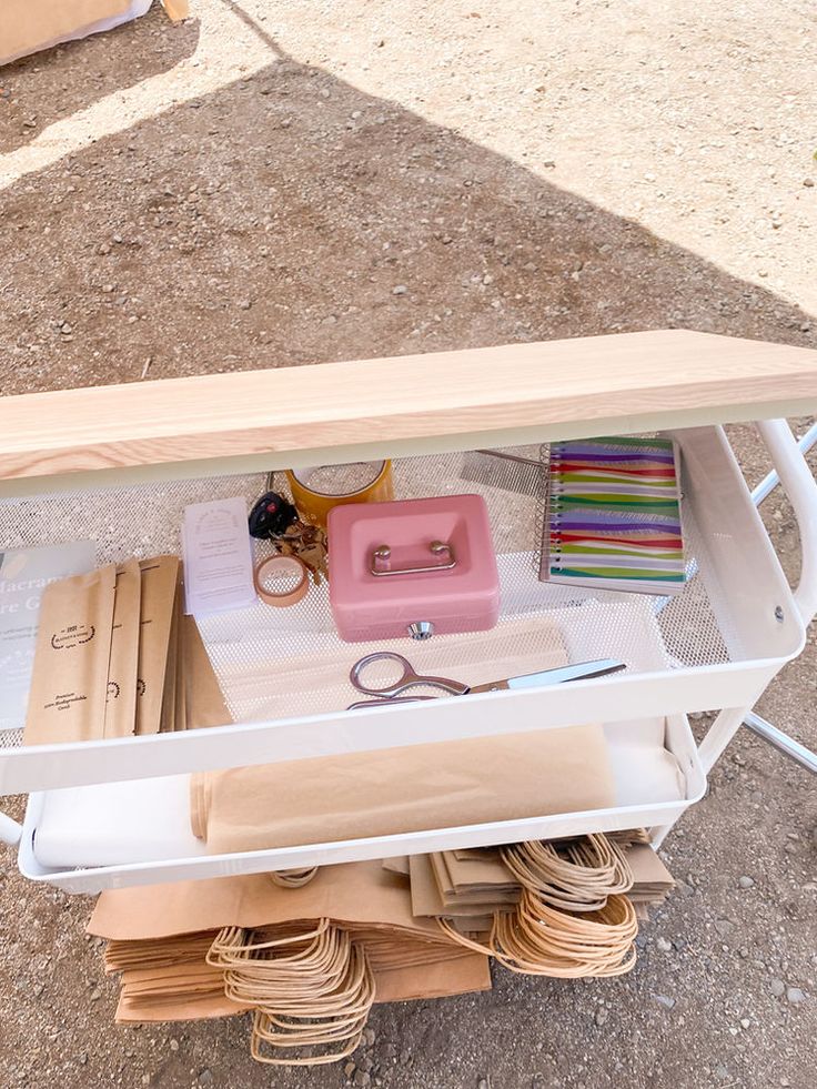 a table with many items on it and some scissors in the bottom shelf next to them