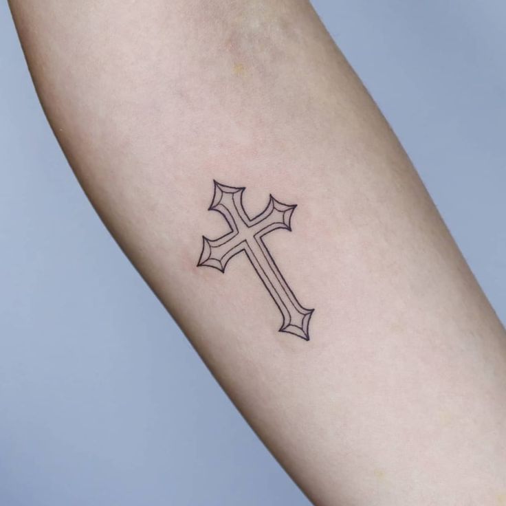 a small cross tattoo on the arm