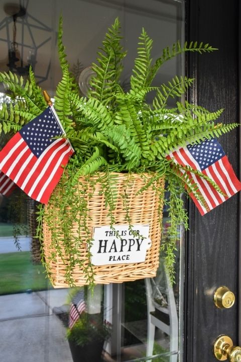 a basket filled with plants and flags hanging from the front door