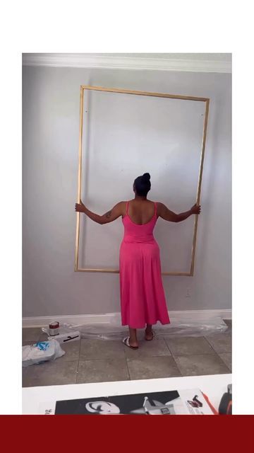 a woman in a pink dress holding up a frame