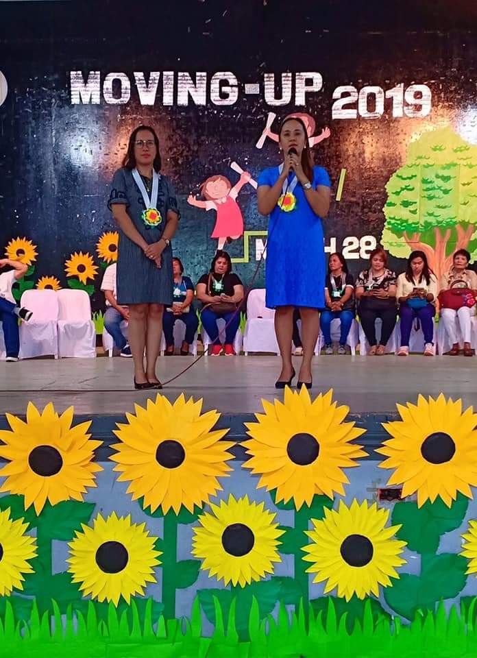 two women standing on stage with sunflowers in front of them