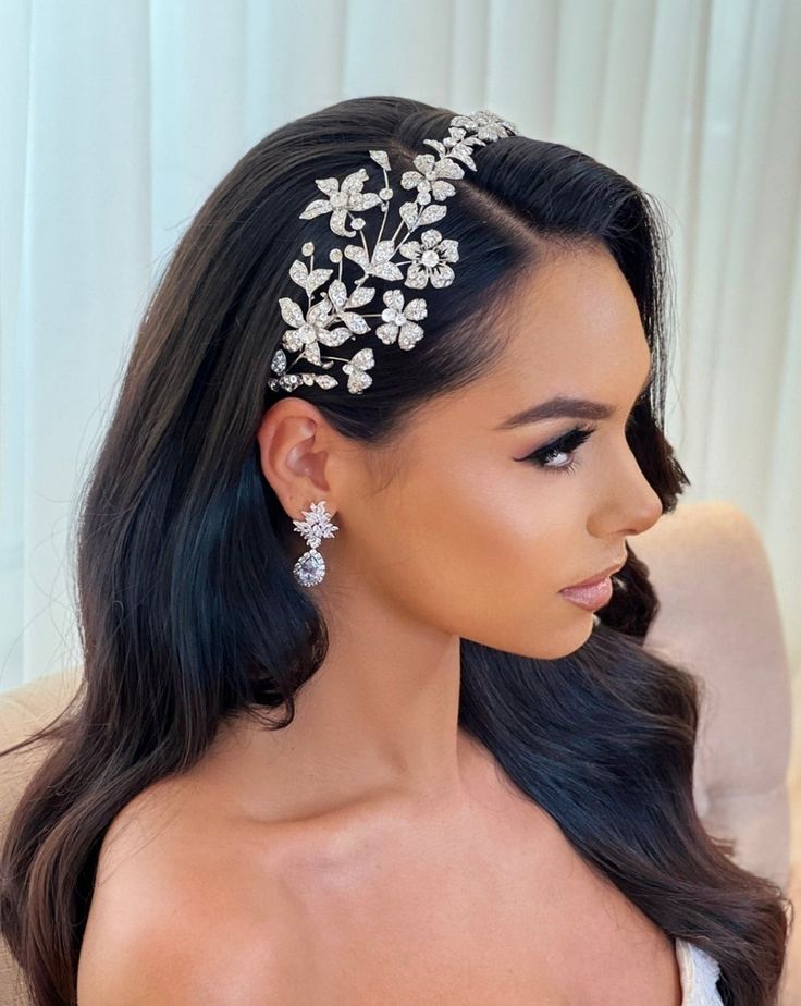 a woman with long black hair wearing a white flowered headpiece on her head