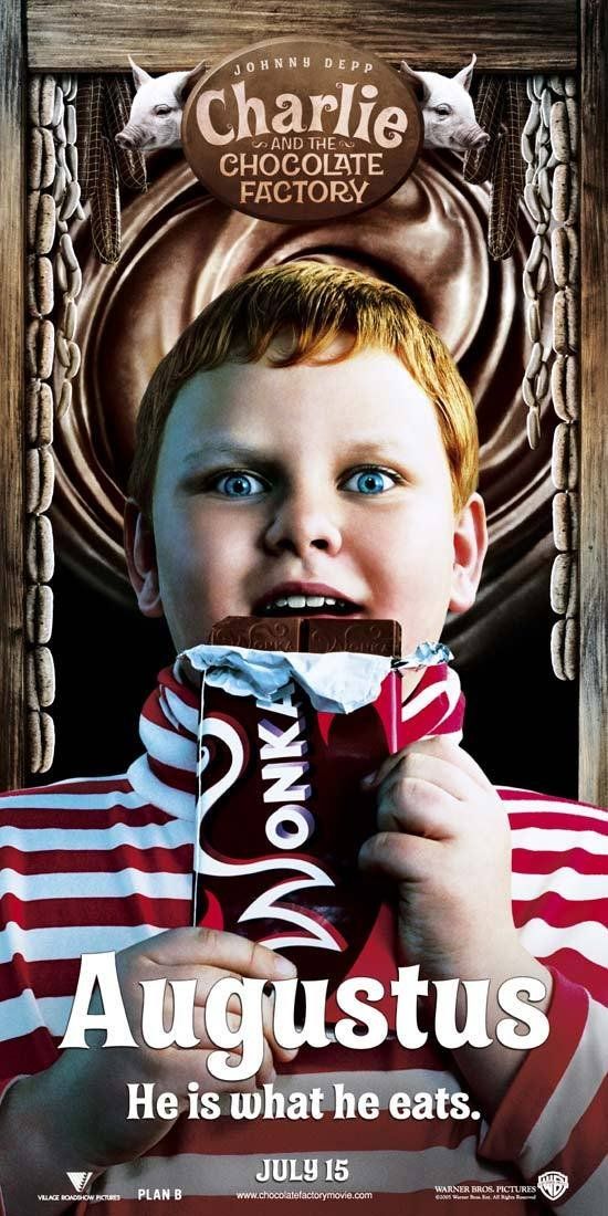 a young boy eating a chocolate bar in front of a poster