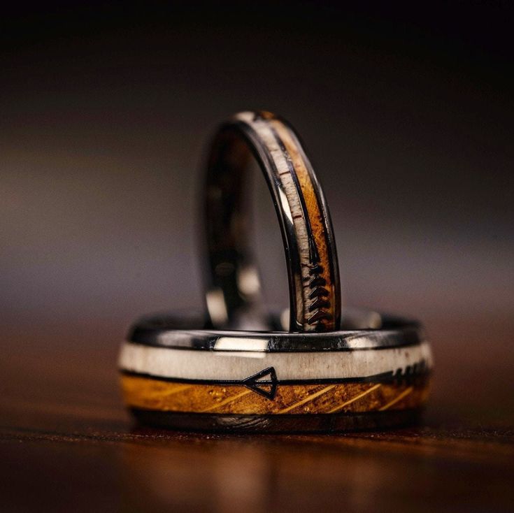 two wedding rings made out of wood and metal with an arrow on the inside of them