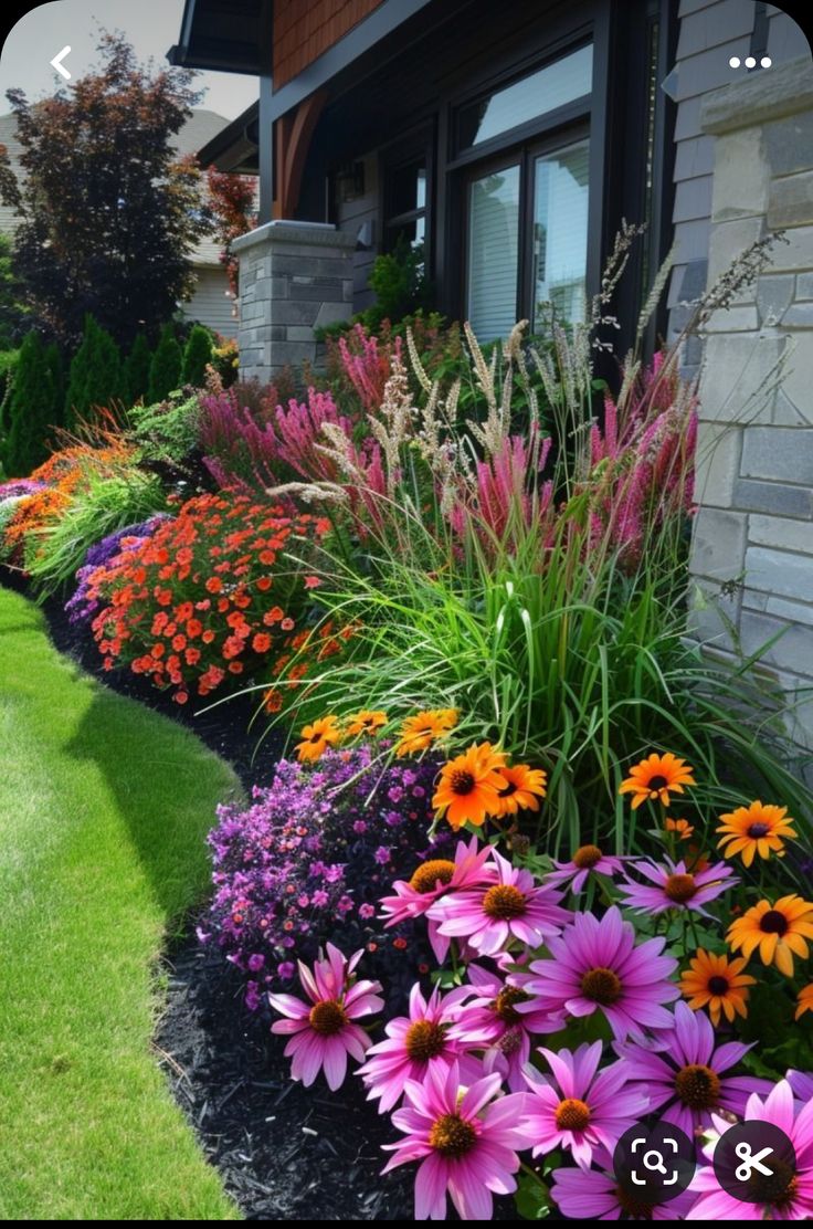 colorful flower garden in front of house with grass and flowers on the side walk area