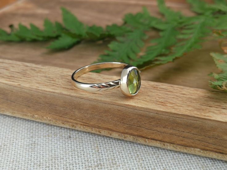 This nature inspired solid gold ring features a beautiful bright green peridot. On one side of the stone the band is adorned with carved leaves, on the other side the band is adorned with a gold ball. The ring band is made out of 1mm thick 14k gold and is about 2 mm wide. Details: - this ring measures a US size 6.25 (16.75mm)  - the peridot measures about 9mm x 6.5mm - the band is approximately 2mm wide and is 1mm thick - the material used recycled 14k solid gold You will receive the exact item as pictured, but please note that colors may vary slightly depending on the screen you are using. This jewel is made with care and much love and will be packaged accordingly. Whether you will buy for yourself or for someone else, the jewel will arrive ready for gifting! All my pieces are handcrafted Green Oval Stackable Rings For May Birthstone, Green Amethyst Ring In 14k Gold, Fine Jewelry Peridot Rings For May Birthstone, Peridot Ring Jewelry, Green Peridot Stackable Jewelry, Green Oval Bezel Setting Stackable Rings, Green Oval Stackable Rings With Bezel Setting, Stackable Green Peridot Jewelry, Stackable Green 14k Gold Jewelry