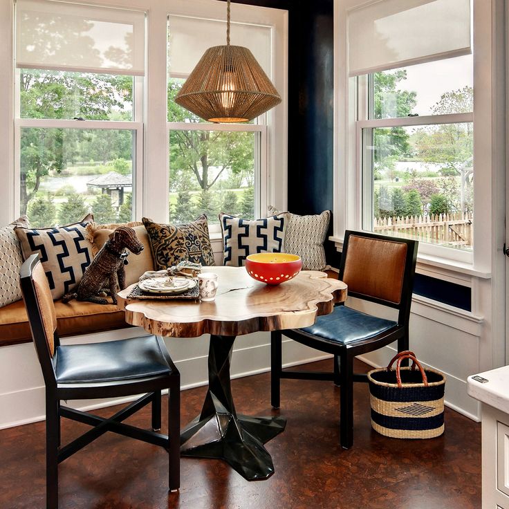 a table with two chairs and a bowl on it in front of three large windows