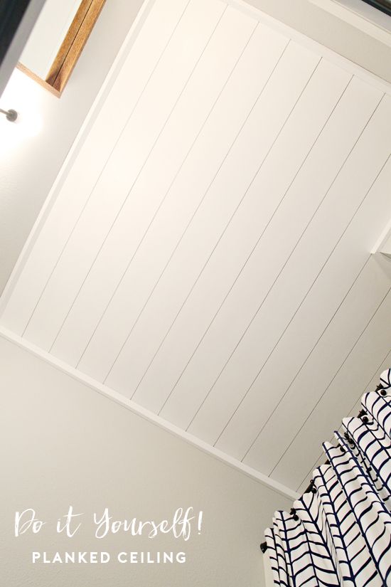 a bed sitting under a window next to a white wall and wooden beams on the ceiling