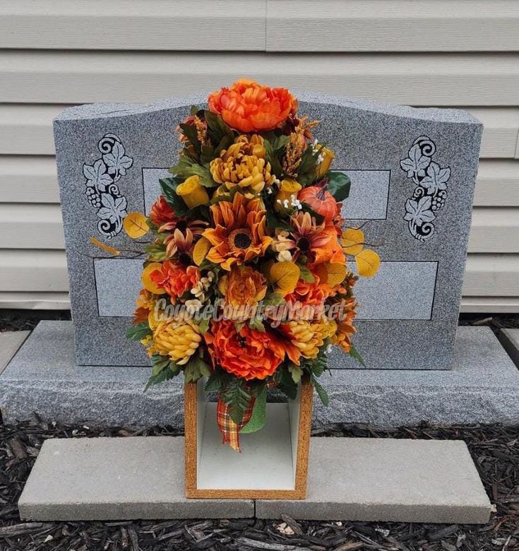 an arrangement of flowers is placed in front of a grave