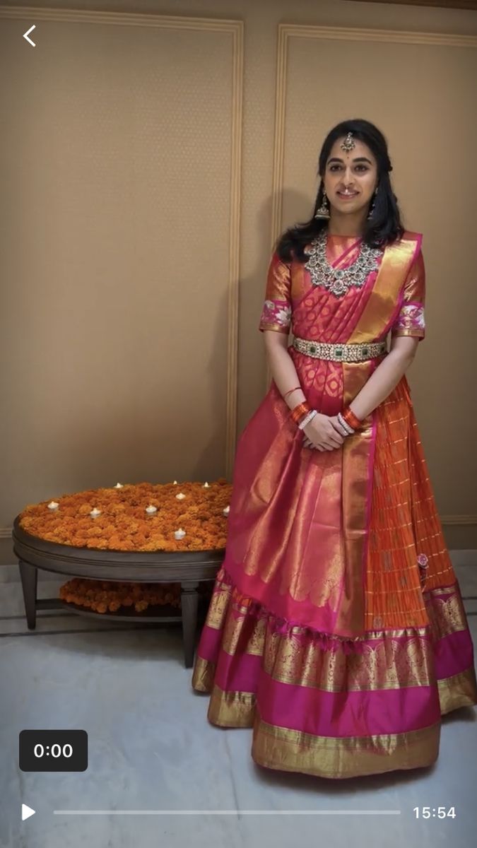 a woman in a red and gold dress standing next to a table