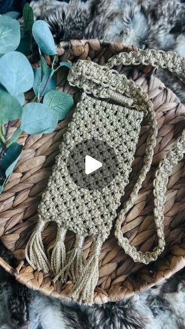 a crocheted bag sitting on top of a basket next to some plants and leaves