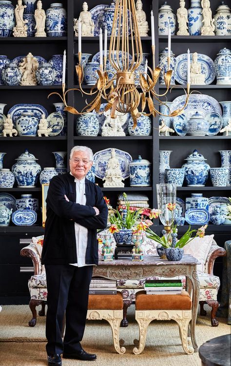 an older man standing in front of a table with blue and white china on it