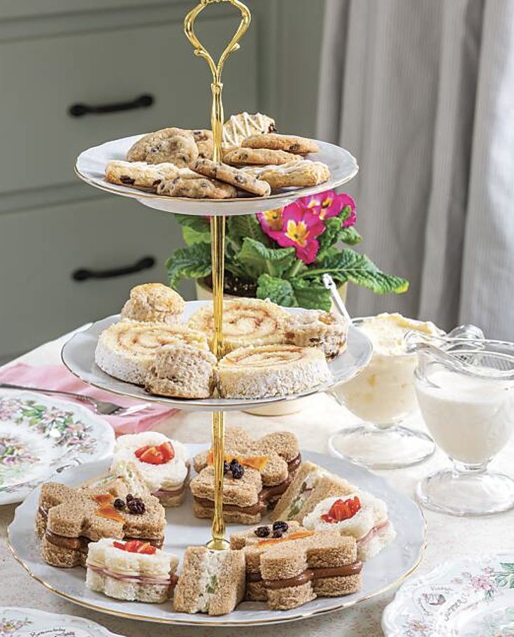 three tiered trays filled with sandwiches and pastries on top of a table